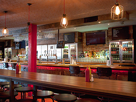 Accent lighting has been used to highlight the range of beers in the counter-top fridges and on tap. Different styles of seating have been used throughout the venue.