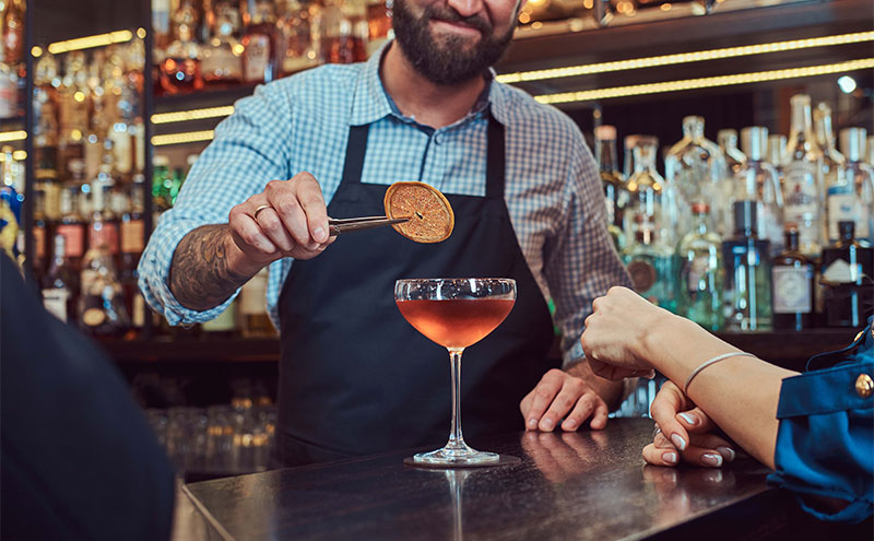 Bartender adding garnish to a cocktail.