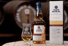 A bottle of whisky sits next to a dram