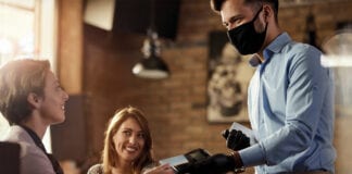 Waiter with face mask taking payment from customer