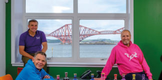 Boe gin owners infront of a window facing the forth road bridge with a selection of Boe products