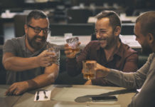 Three men cheers with glasses of whiskey in a pub