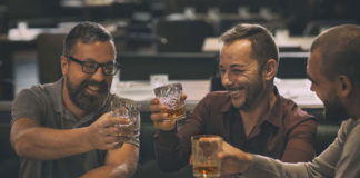 Three men cheers with glasses of whiskey in a pub
