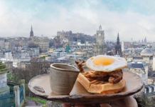A plate of food topped with a fried egg sits with the Edinburgh skyline behind