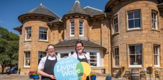 Staff stand outside the Royal gold hotel holding a living wage sign