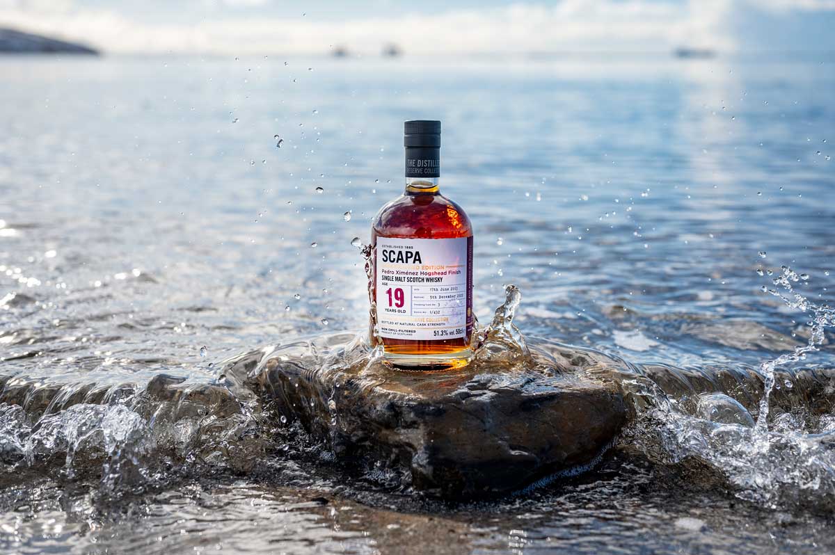 Scapa-Noust whisky bottle sits on a rock in the sea
