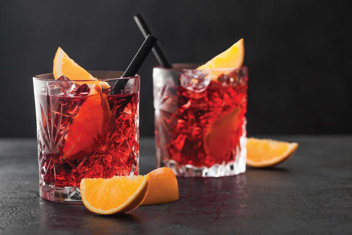 Negronis on a bar with orange slices