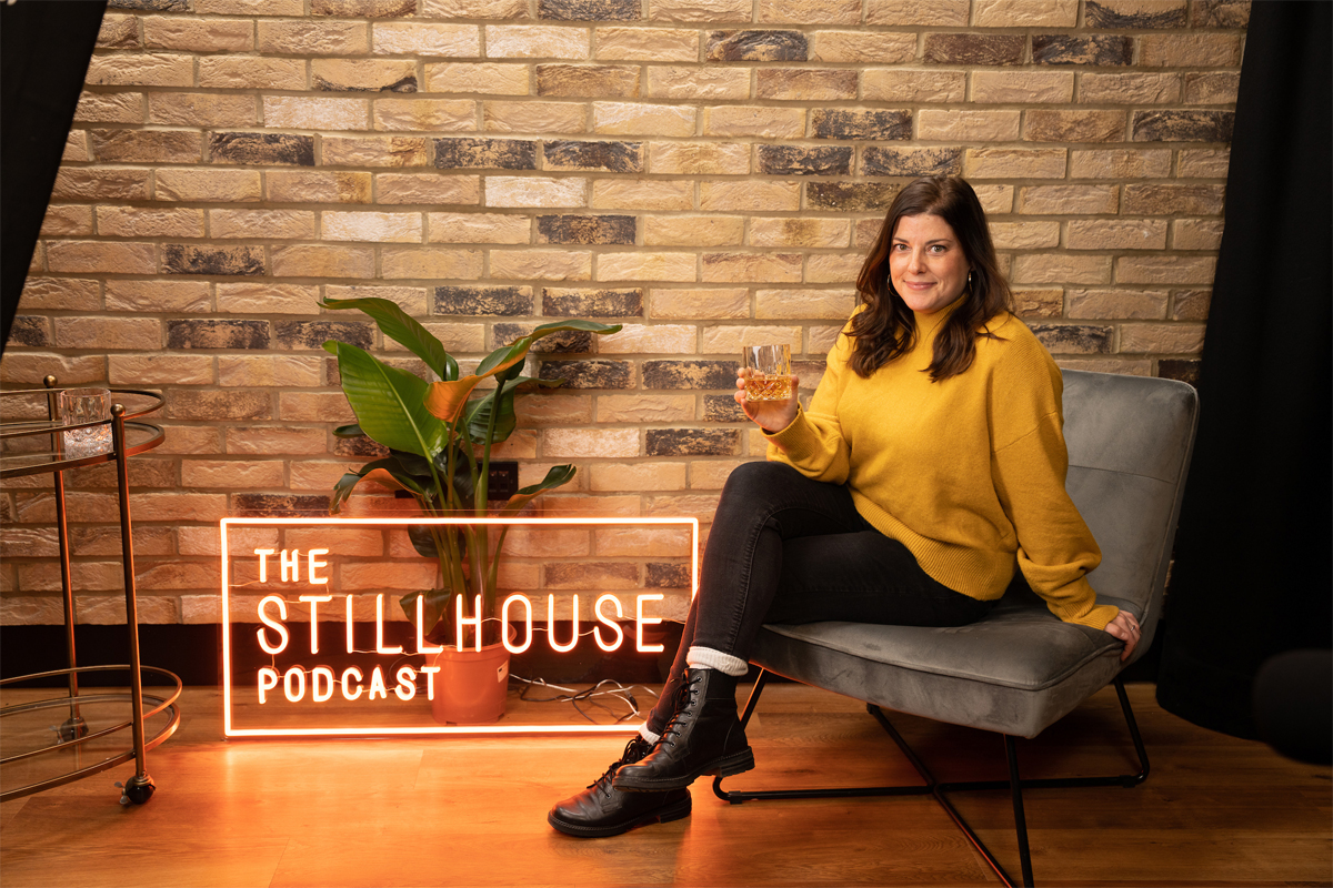 The Stillhouse Podcast sign with woman sitting on chair