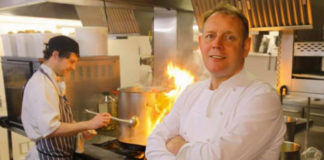 Chef Brian Maule in a kitchen, with flames behind