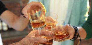 Friends toast each other with whisky glasses