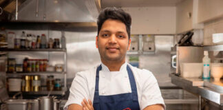 a chef stand with his arms folded in an industrial kitchen
