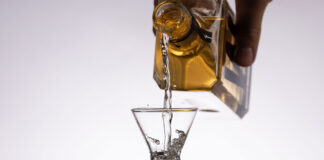 gin is poured from a bottle into a shot glass