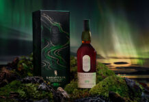 lagavulin whisky carton and bottle on mossy terrain with a green sky in the background