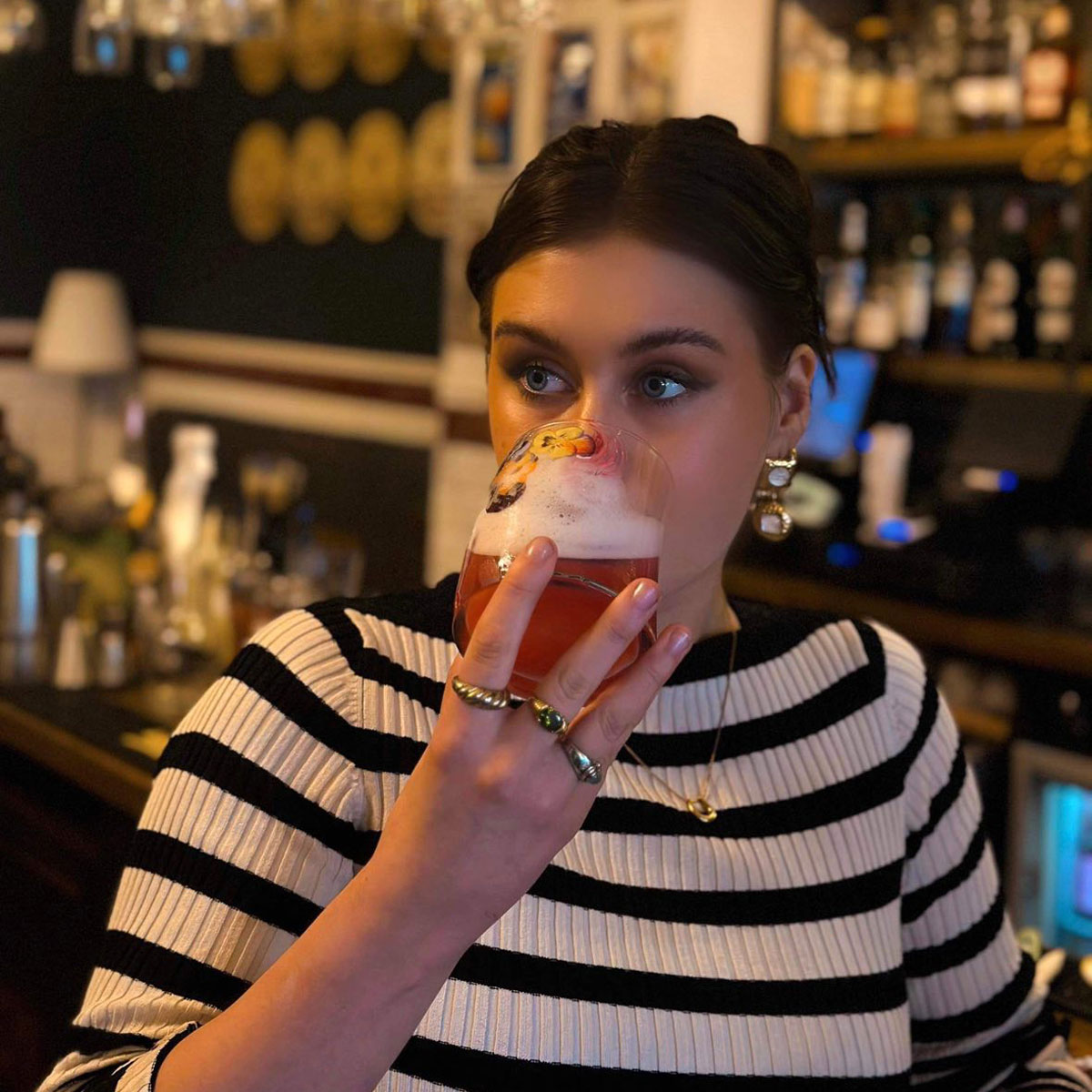 Girl in striped top drinks a cocktail