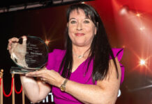 A woman holds up an award