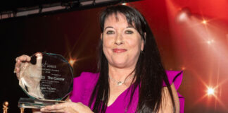 A woman holds up an award