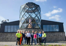 A team of staff outside a stylised Hebridean distillery