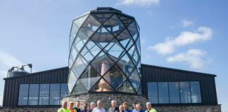 A team of staff outside a stylised Hebridean distillery