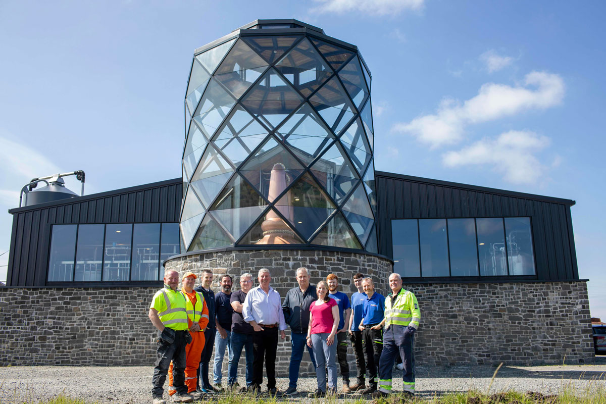 A team of staff outside a stylised Hebridean distillery