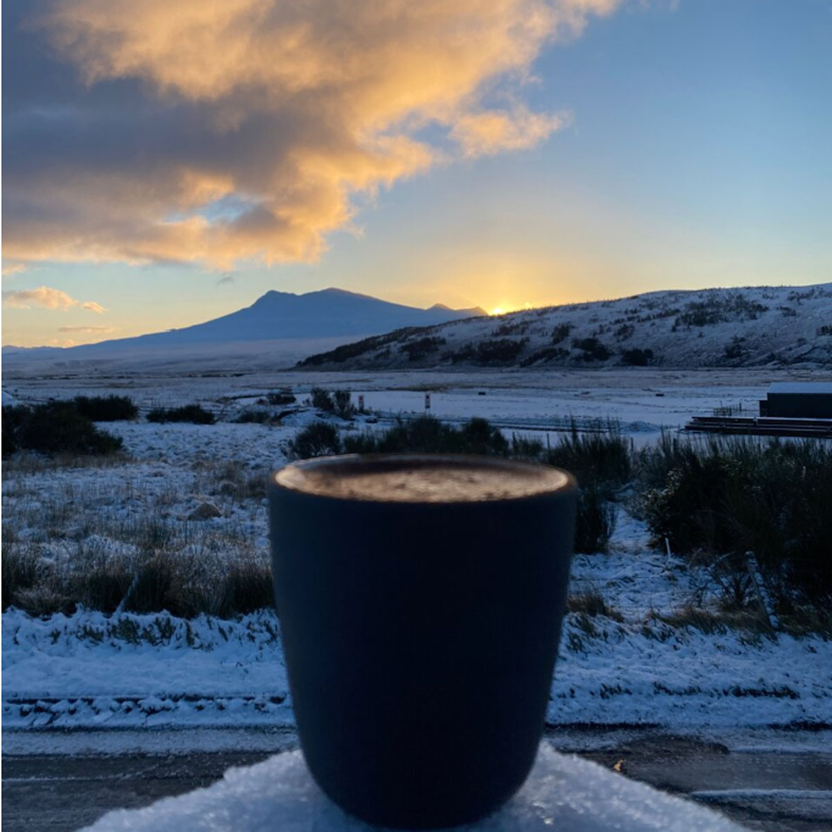 A cup of coffee against a Scottish Highlands sunrise