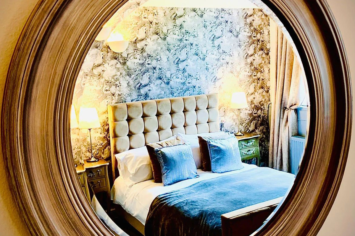 A hotel bedroom reflected in a round mirror