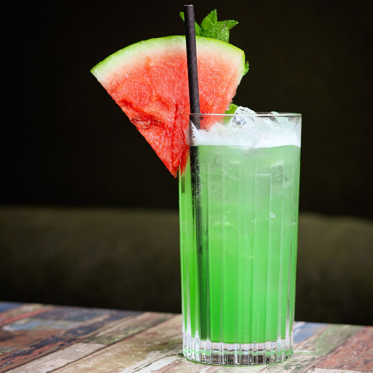 a green drink with a slice of watermelon on its edge