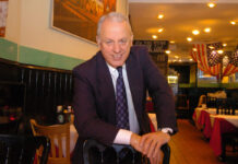 a smiling man wearing a suit in a restaurant