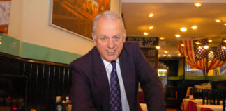a smiling man wearing a suit in a restaurant