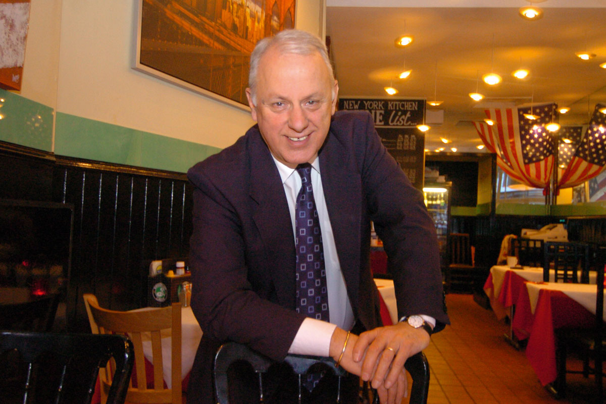 a smiling man wearing a suit in a restaurant