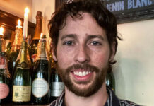 A bearded young man behind a bar