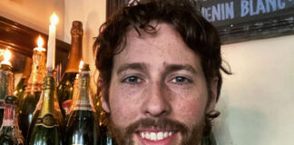 A bearded young man behind a bar