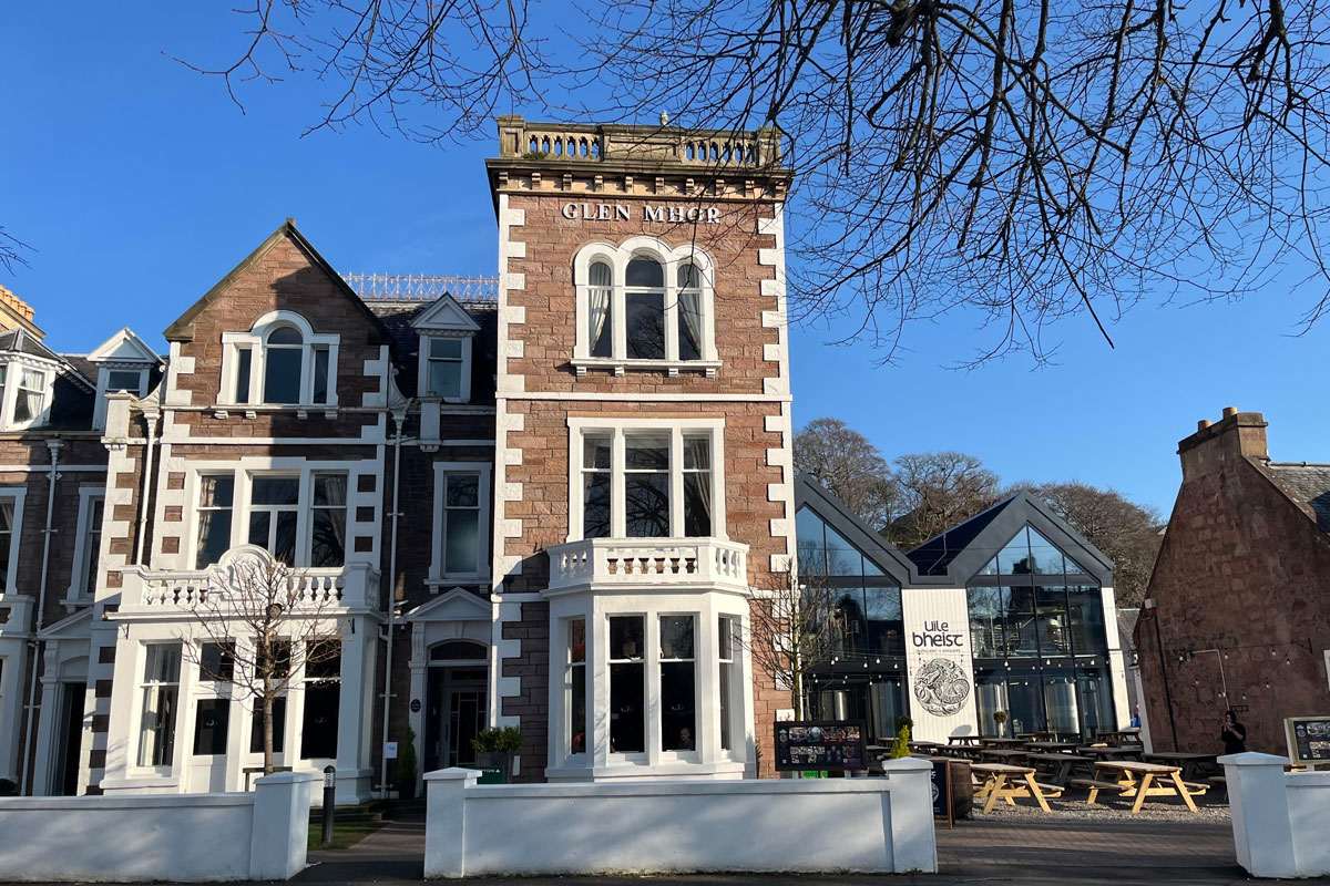 An old fashioned Highlands hotel, with a modern extension, pictured in sunshine