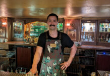 A bartender behind his bar, wearing a panda-themed apron