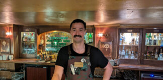 A bartender behind his bar, wearing a panda-themed apron