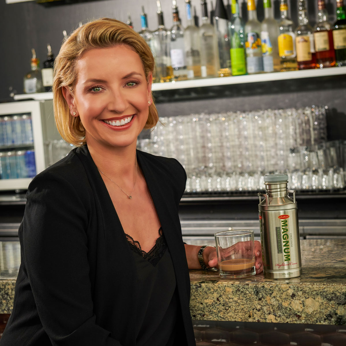 Glamorous blonde woman stands smiling at a bar