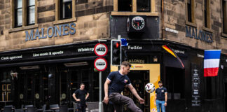 A man plays with a football in the street