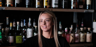 A young blonde woman serves behind a bar