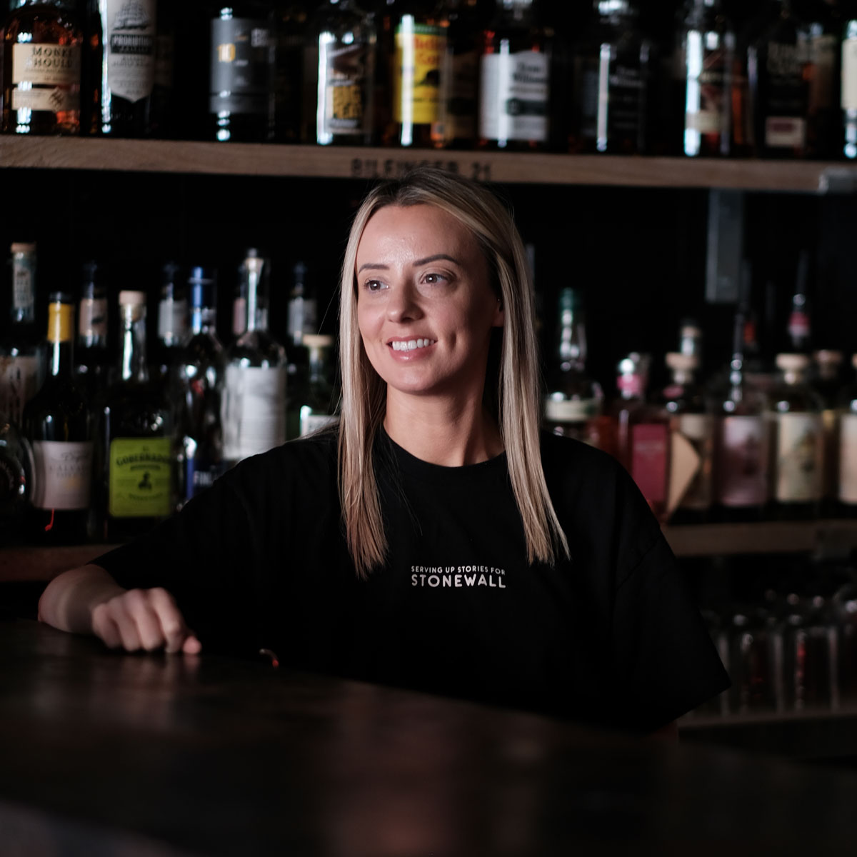 A young blonde woman serves behind a bar