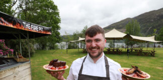 a chef holds two plates of food in a lochside garden at glenfinnan house hotel