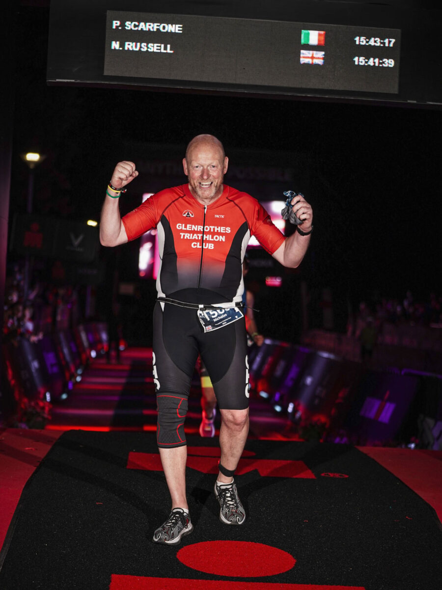 A bearded man in red lycra celebrates as he crosses the finish line of a race