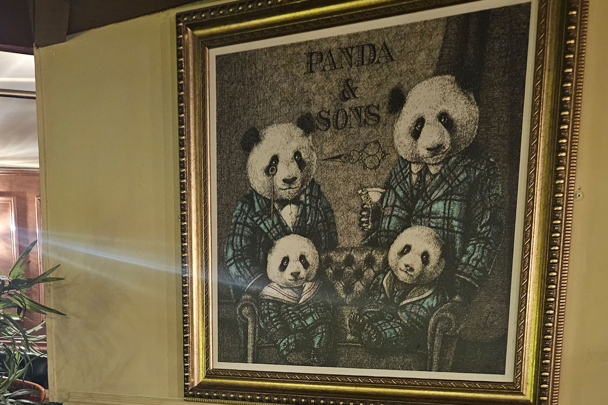 a framed picture of a family of pandas in tweed suits