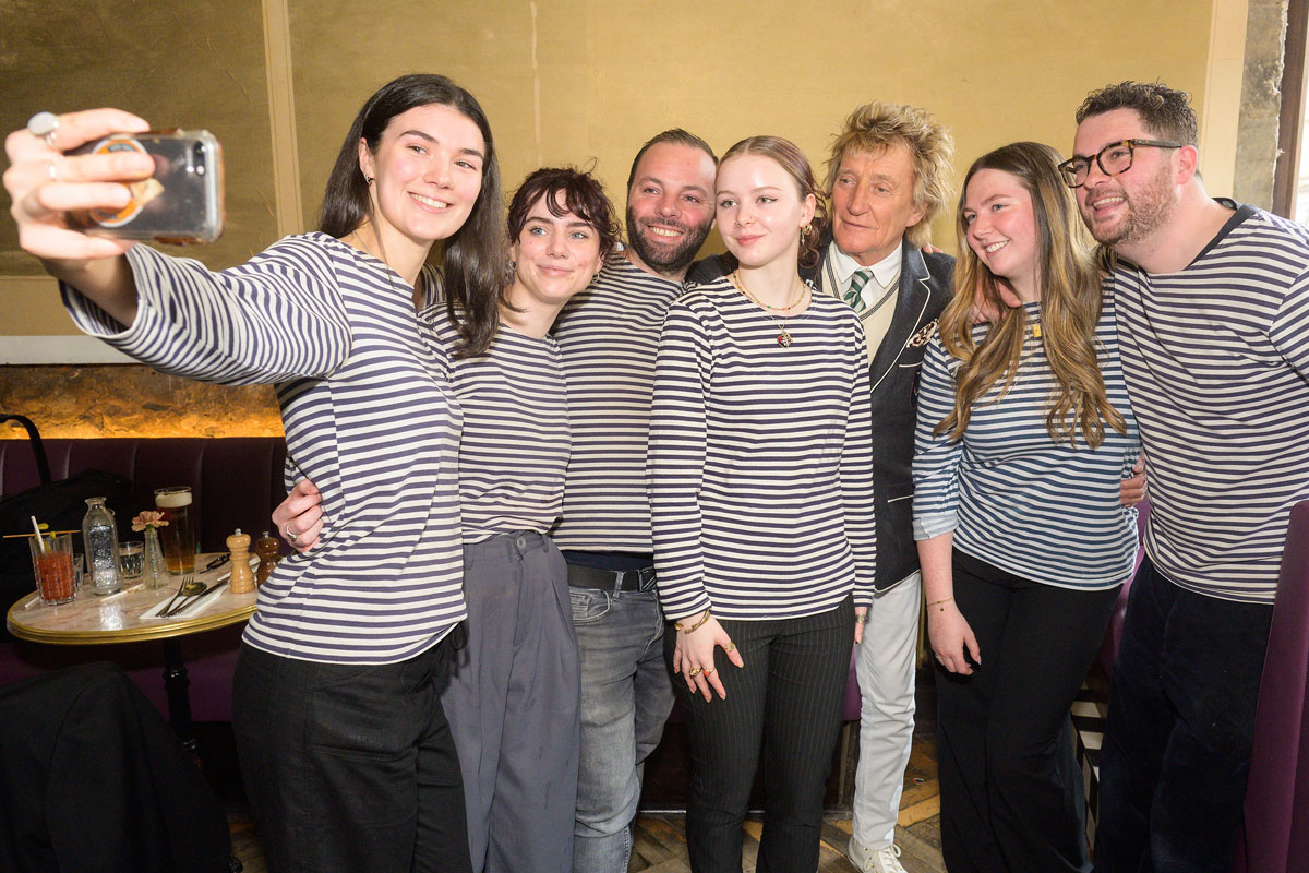 Venue staff in stripey tops take a selfie with a celebrity