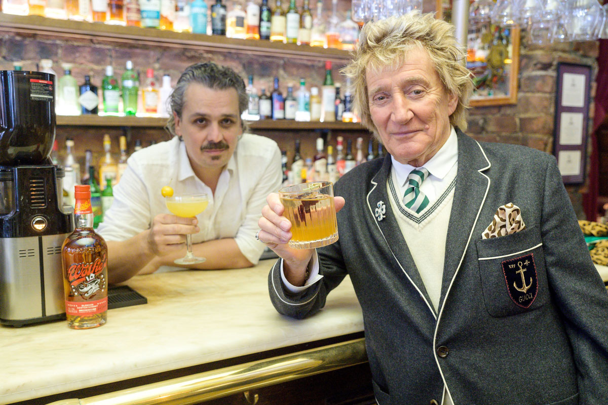 A man in a boating blazer drinks whisky at a bar