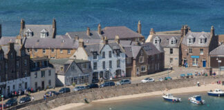 A traditional pub alongside houses on a Scottish harbour