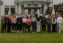 A group of hotel staff apprentices gathered on a hotel lawn