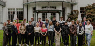A group of hotel staff apprentices gathered on a hotel lawn