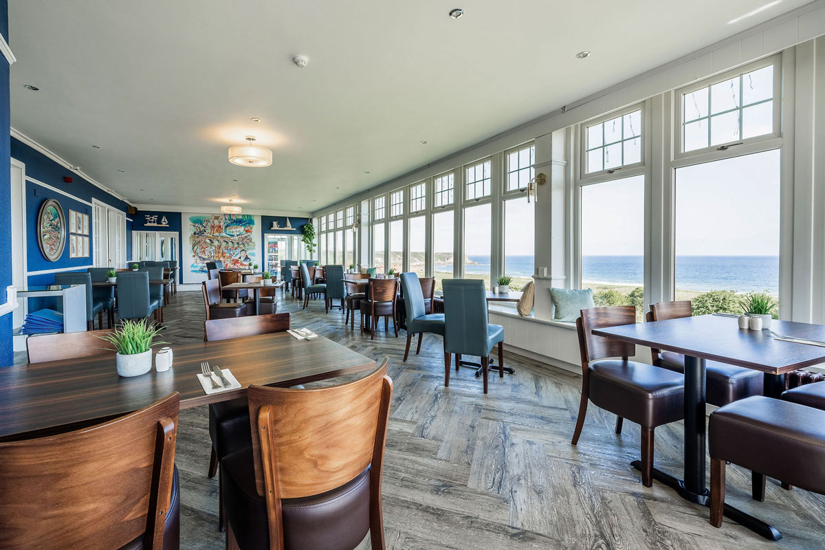 A hotel dining room with windows out onto a sea view