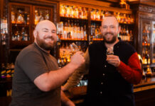 Two cheerful bearded men drink whisky in a bar
