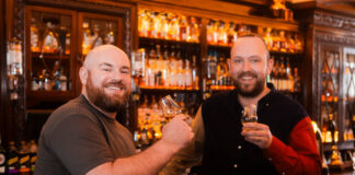 Two cheerful bearded men drink whisky in a bar