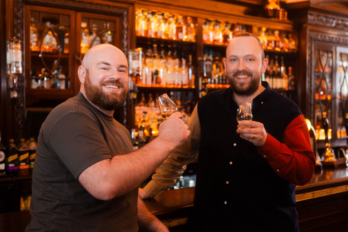 Two cheerful bearded men drink whisky in a bar